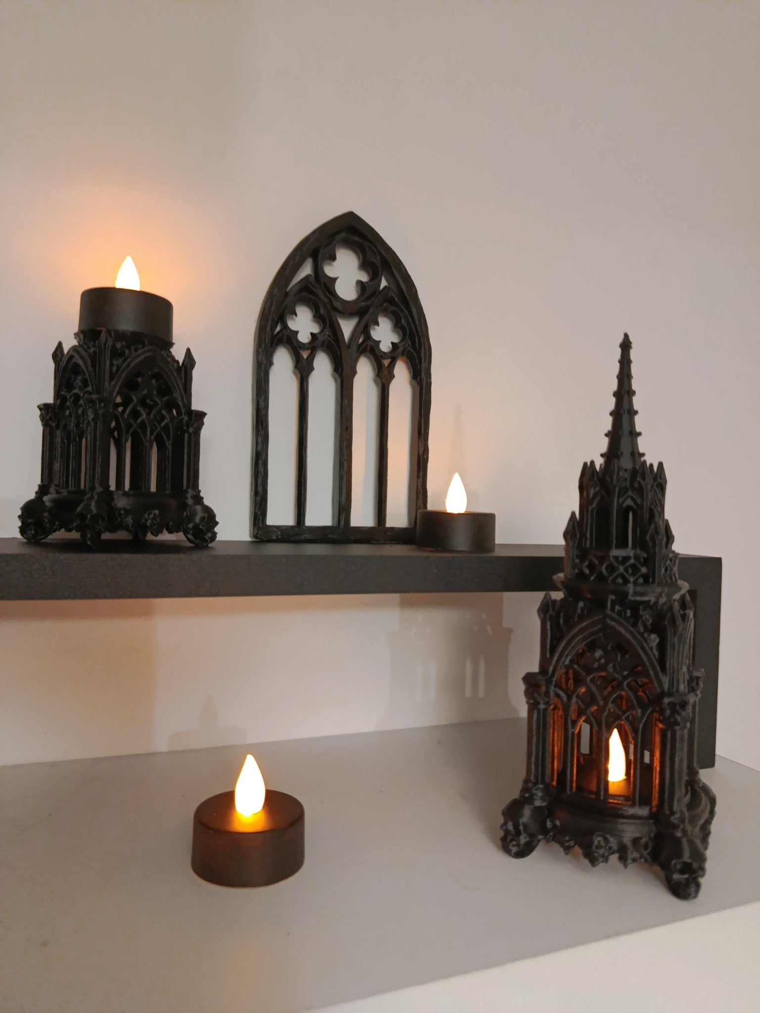 A set of gothic art on a white table with candles illuminating them